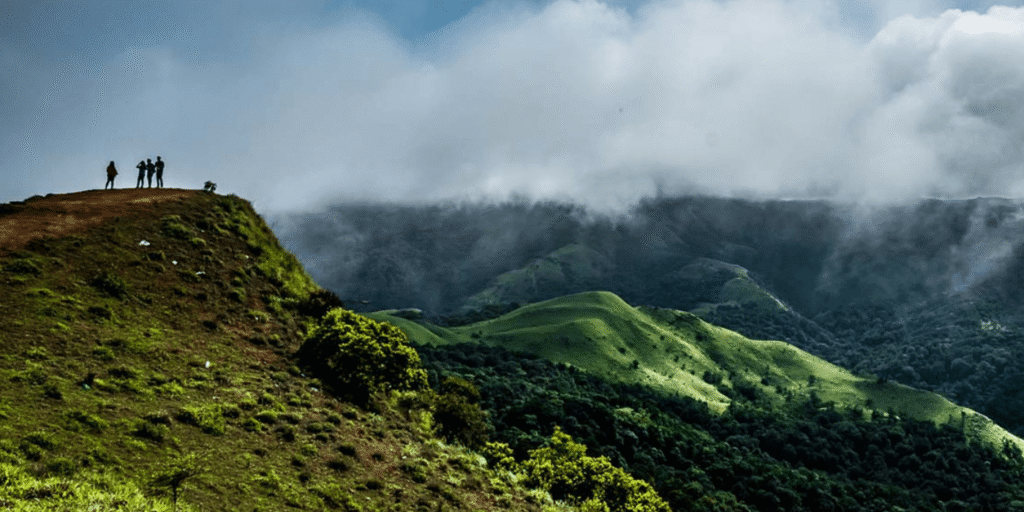  A peaceful view of Coorg, Karnataka, featuring mist-covered coffee plantations, dense forests, and gently rolling hills under a cloudy sky.